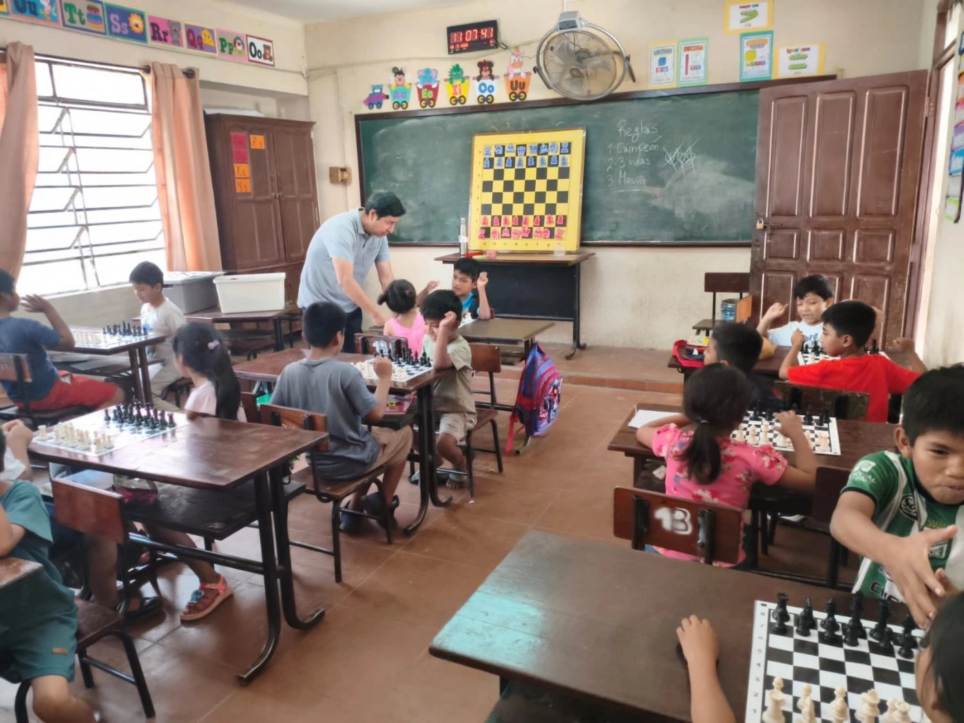 Clase de P.E.C.U. en el colegio 3 de Mayo: el profesor explica en el tablero mural y los alumnos siguen desde sus mesas